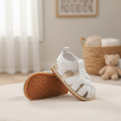 White baby sandals with soft flexible sole photographed on a neutral background